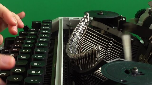 The girl is typing on a retro typewriter on a green background. Chromakey.