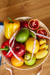 Top view of Nutritionist, dietitian workplace with measuring tape and bowl with healthy vegetables and fruits