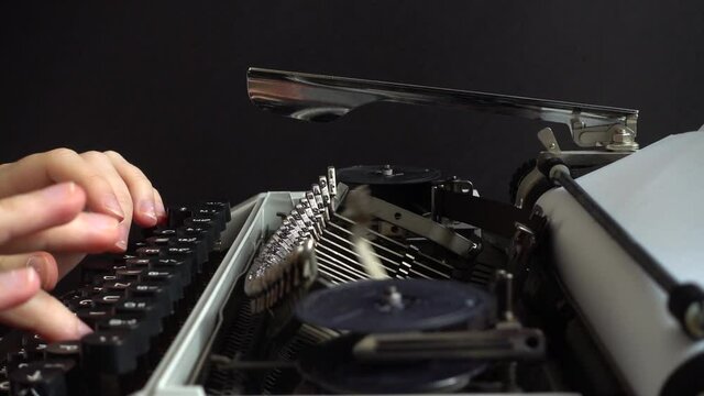 The girl is typing on a retro typewriter. Slow motion.