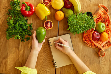Woman planning, writing weekly meals on a meal planner note or diet plan