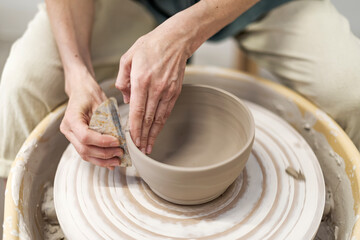Hands of young woman working on pottery wheel in cozy workshop and making vase or mug - obrazy, fototapety, plakaty