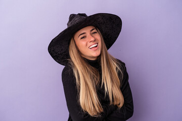 Fototapeta premium Young Russian woman disguised as a witch celebrating Halloween isolated on purple background laughing and having fun.