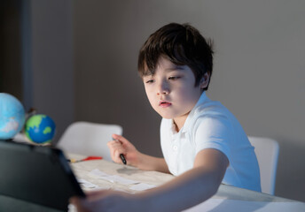 School kid using tablet for his homework,Child boy doing homework by using digital tablet searching information on internet after back from school,E-learning, Home schooling education concept