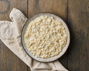 Oatmeal porridge. Traditional bunting breakfast served in ceramic bowl on wooden background. Vegetarian and nutritious vitamin morning eating. Classic hot homemade dietary meal