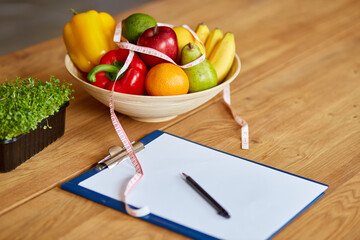 Top view of Nutritionist, dietitian workplace with measuring tape and bowl with healthy vegetables...