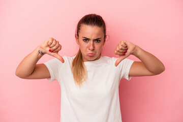 Young Russian woman isolated on pink background showing a dislike gesture, thumbs down....