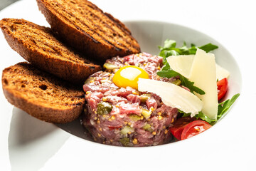 Tartare from beef with egg, and onions, fresh herbs, bread. French cuisine. Food recipe background. Close up