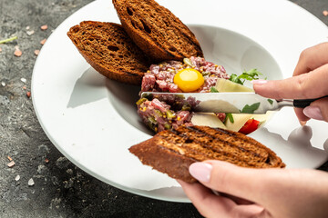 Tartare from beef with egg, and onions, fresh herbs, bread. French cuisine. Food recipe background. Close up