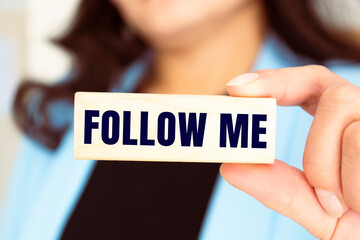 women hand pushes a piece of wood with text Follow Me from other pieces of wood