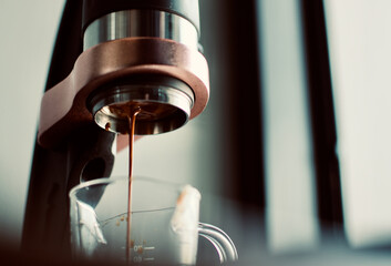 a shot of a coffee with manual espresso machines drop in a transparent cup
