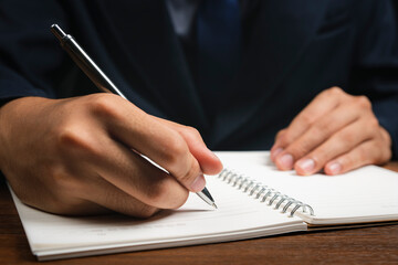Fototapeta premium Businessman hand with pen writing on notebook. close-up