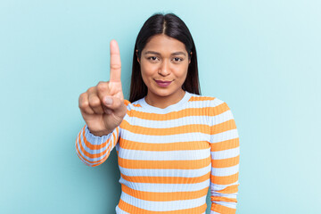 Young Venezuelan woman isolated on blue background showing number one with finger.