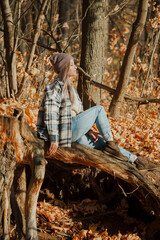 a blonde girl in a plaid shirt in the autumn forest