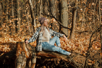 a blonde girl in a plaid shirt in the autumn forest