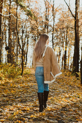 
a blonde adult girl walks in the autumn forest. a walk in the fresh air alone