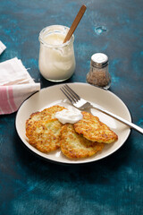 Potato fritters on plate with sour cream