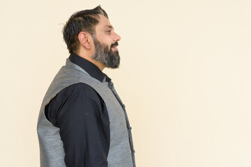 Profile view portrait of handsome bearded Indian man against plain background