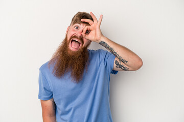 Young caucasian ginger man with long beard isolated on white background excited keeping ok gesture on eye.