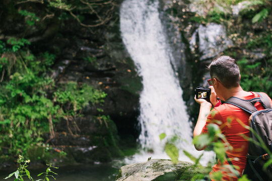 Man taking pictures of a waterfall in the forest