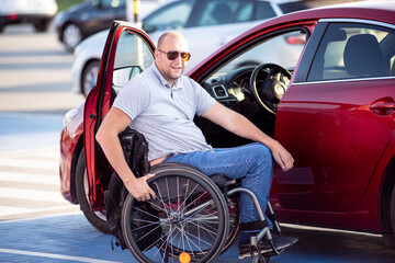 Fototapeta na wymiar Person with a physical disability getting in red car fom wheelchair