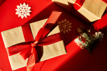 Top view Christmas eco friendly packaging kraft paper and fir branches gifts for the Holiday season on red background, hard light