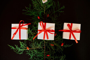 Top view Christmas eco friendly packaging kraft paper and fir branches gifts for the Holiday season on black background, hard light