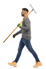Gardener is walking and holding rake on a shoulder. Side view. Studio shot, isolated. - 463388607