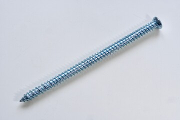 Single long silver screw for windows or frames on white background