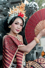 Portrait of a beautiful balinese woman in traditional costume and hand fan, indonesian girl, hindu temple background, Bali.