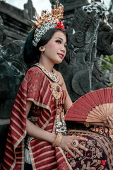 Balinese woman in traditional costume and hand fan, indonesian girl, hindu temple background, Bali.