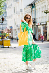 Fototapeta premium Young beautyful woman with yellow linen eco bag on city background.
