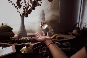 A crystal ball is floating above a woman's hand on her esoteric witch altar