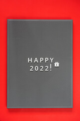 Happy 2022 lettering on chalkboard. Red background. Blackboard with letters, New Years holiday.