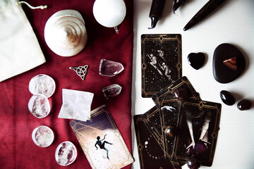 Altar with tarot cards on a burgundy scarf with several white quartz crystals, runes, black candles...