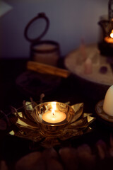 Detail of a white candle on a golden flower-shaped candle holder, on a witch's altar to perform...