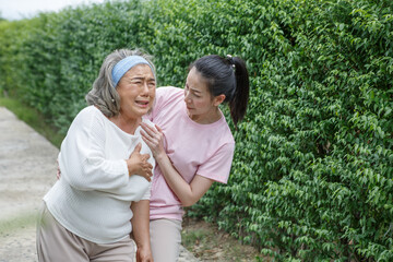 Fototapeta premium asian young daughter caring for sick senior mother To suffering chest pain or Heart attack at home . old mom suffering from illness has a adult caregiver woman to take care