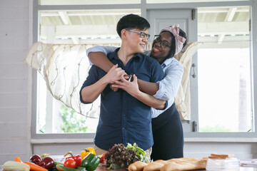 diverse couple Asian husband and african american wife cooking and tasting food together in kitchen at  home .