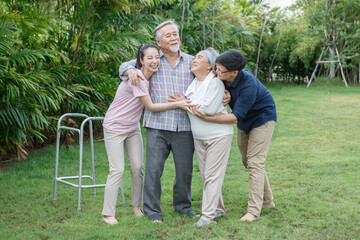 asian senior father trying walk with walker and adult son daughter wife support in gaden at home. old man disabled walking and caregiver young man helping in back yard . health care family lifestyle