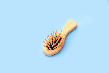 Wooden comb brush on blue background, eco concept
