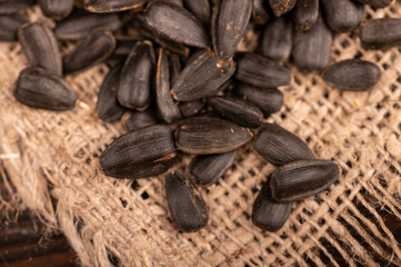 Fried black sunflower seeds scattered on the table, close-up, selective focus.