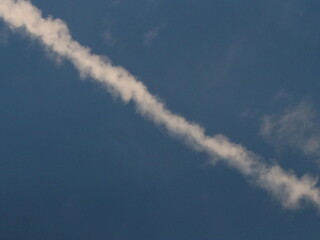Naklejka na ściany i meble White trail from an airplane in the blue sky