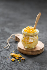 Millet porridge with pumpkin and raisins in a glass pot on a wooden board in rustic style on a dark background