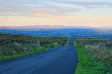 Lonely Road leading to the Eden Valley with the Lake District Mountains on the Horizon, Cumbria, England, UK.
