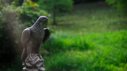 eagle sculpture in the park. plaster eagle, in the autumn city park. close-up, against a background of green grass, summer or autumn season