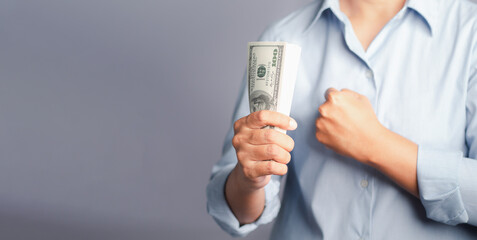 Business and finance concept. Hand holding of a US dollars banknote and fist while standing on gray...