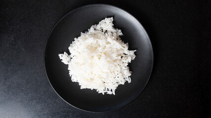 Top view beautiful Streamed rice is placed on a black plate in the center of the picture. and placed on the black tiled floor.