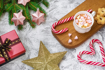New Year's or Christmas composition of marshmellow cup on wooden stand, spruce green branches, gift, star and lollipops