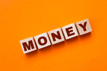Wooden blocks with the lettering Money on top of ascending bar graphs analyzing the statics and...