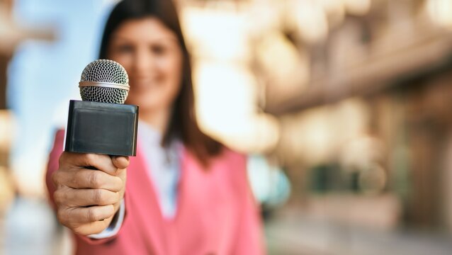 Middle age reporter woman holding journalist mic close to the camera, close up of professional microphone.