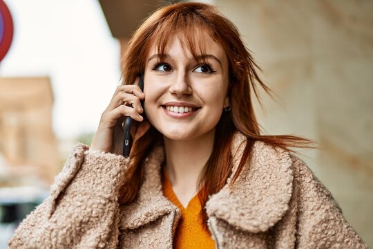 Young redhead girl smiling happy talking on the smartphone at the city.